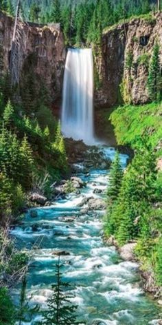 a large waterfall is in the middle of a river with trees on both sides and water running through it