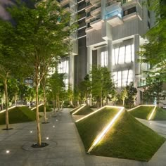 an office building lit up at night with trees in the foreground and grass on the ground