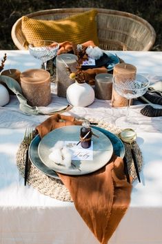 an outdoor table set with plates, napkins and other items for a dinner party