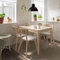 a dining room table and chairs with plants on the window sill in front of them