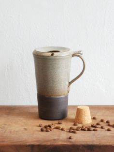 a coffee cup sitting on top of a wooden table next to a pile of coffee beans