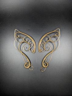 Just the right touch to spice up your fantasy costume. Add these beautiful ear cuffs to your elf costume for your next Ren Faire or use them as a fun bit of jewelry at your next D&D event. Golden Brass curls and intricate woven wire with a clear finish make these lovely ear cuffs a must have for your next fantasy event.  These ear cuffs have been polished to a bright shine and sealed with a clear coat. No piercings are necessary for these elf ears to stay in place, the back wire rides behind the Elf Jewelry, Dragon Ear Cuffs, Elf Ear Cuff, Wrapping Jewelry, Elf Costume, Elf Ears, Wrap Earrings, Fantasy Costumes, Ear Cuffs