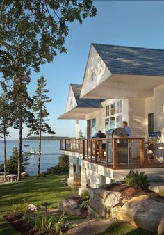 two people are sitting on the porch of a house overlooking the water and boats in the bay