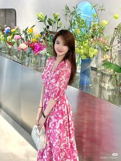 a woman standing in front of flowers holding a purse