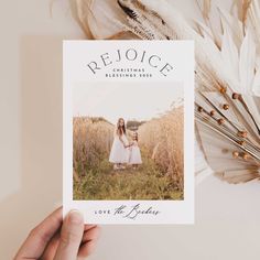 a person holding up a card with the words rejoice on it in front of some feathers