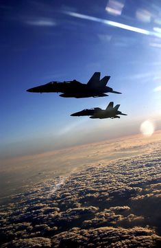 two fighter jets flying in the sky above clouds