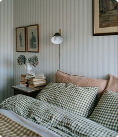 a bed sitting next to two framed pictures and a lamp on top of a table