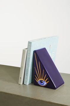 an open book sitting on top of a table next to a purple box with eyes