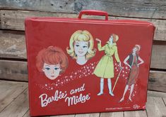 a red suitcase with pictures of barbies and models on the front, sitting on a wooden floor