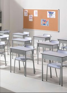 there are many desks and chairs in the room with a bulletin board on the wall