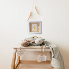 a teddy bear sitting on top of a wooden bench next to a blanket and stuffed animal