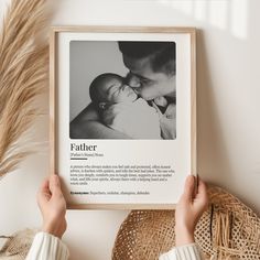 a person holding up a framed photo with the words father on it next to a plant