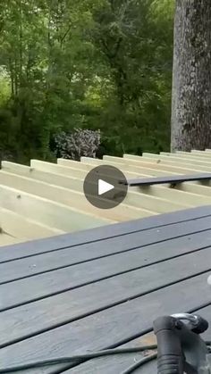 a camera is sitting on top of a wooden deck in front of some trees and bushes