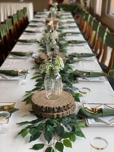 a long table with place settings and greenery