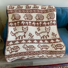 a crocheted afghan sitting on top of a blue couch next to a rug