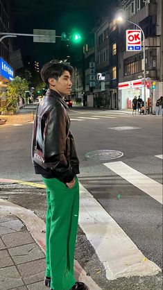 a man in green pants standing at an intersection