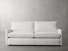 a white couch sitting on top of a floor next to a gray wall in an empty room