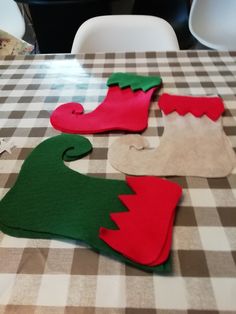 three felt christmas stockings sitting on top of a checkered tablecloth covered dining room table