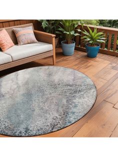 a large round rug on a wooden deck next to a couch and potted plant