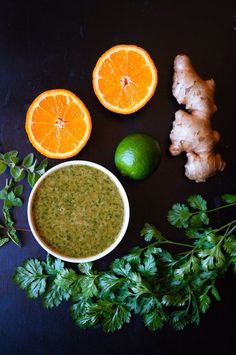 an assortment of fresh fruits and vegetables on a black surface, including oranges, ginger, celery