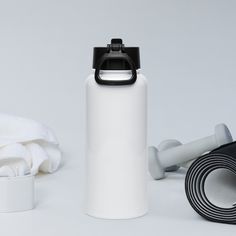 a white water bottle with a black lid next to a rolled up towel and yoga mat