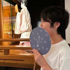 a young boy holding up a paper plate in front of him and looking at the mannequins