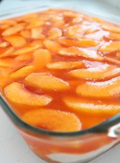 a glass dish filled with sliced peaches on top of a table