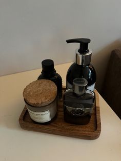 a soap dispenser sitting on top of a wooden tray next to a bottle of lotion