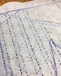 a close up of a piece of cloth on a table with a needle and thread