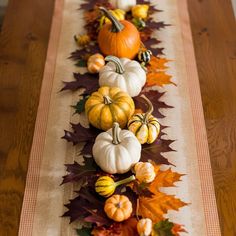 a long table with pumpkins and leaves on it