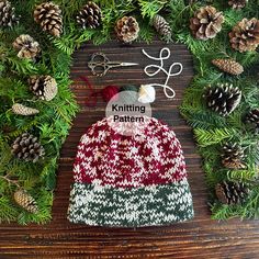 a knitted hat sitting on top of a wooden table next to pine cones and needles