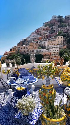 blue and white plates with flowers on them in front of a cityscape that is overlooking the ocean