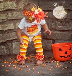 This sweet Halloween Candy Corn outfit for baby girls is a complete set, personalized with a candy corn and name embroidered on the bodysuit. The leg warmers have bows securely sewn on, and the hairbow is handmade with many fun ribbons and over the top with feathers. The bow clips onto the headband.  What's included? * bodysuit with name  * leg warmers  * Hairbow with headband  Size newborn to 6m will receive 8" leg warmers and a 5" bow. Size 9m to 24m will receive 12" leg warmers and a 7" bow.