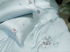 the comforter is made up with blue sheets and white flowers on it, along with two pillows