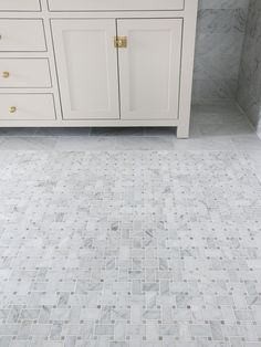 a bathroom with white cabinets and marble flooring