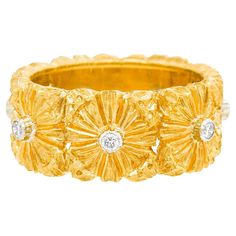 a yellow gold ring with three diamonds on the bottom and two rows of flowers in the middle