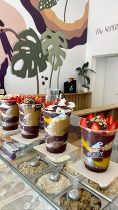 desserts are arranged on trays in front of a wall mural