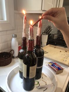 three wine bottles with candles in them sitting on a kitchen counter next to a bottle opener