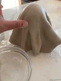 a hand is touching the base of a clay dog