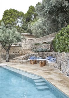 an outdoor swimming pool surrounded by stone walls and steps leading up to the water's edge