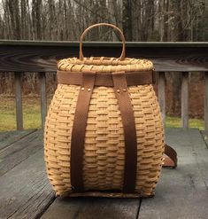 a brown wicker basket sitting on top of a wooden table next to a forest