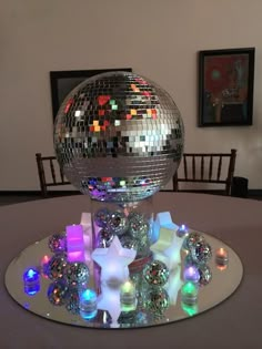 a disco ball sitting on top of a table next to a mirror bowl filled with candles