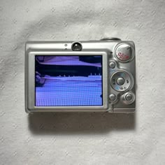 a silver camera sitting on top of a white blanket