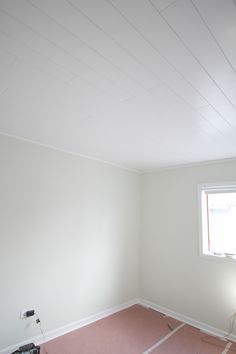 an empty room with white walls and pink carpet