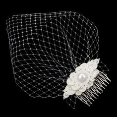 a close up of a hair comb with pearls and netting on the top, against a black background