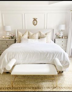 a bedroom with white bedding and gold accents