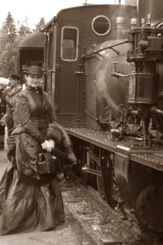 an old photo of a woman standing next to a train