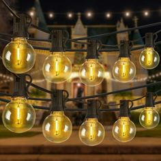 a bunch of light bulbs hanging from a wire in front of a building at night