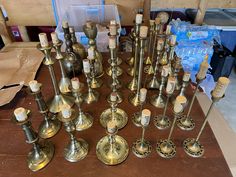 an assortment of brass candles are displayed on a table