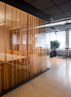 an office with glass partitions and chairs in the center, along with potted plants